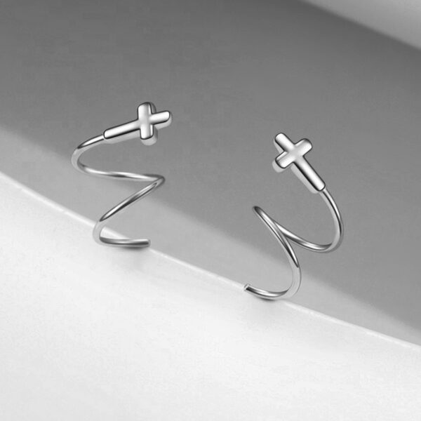 Detail dámské stříbrné náušnice spirálky s křížkem