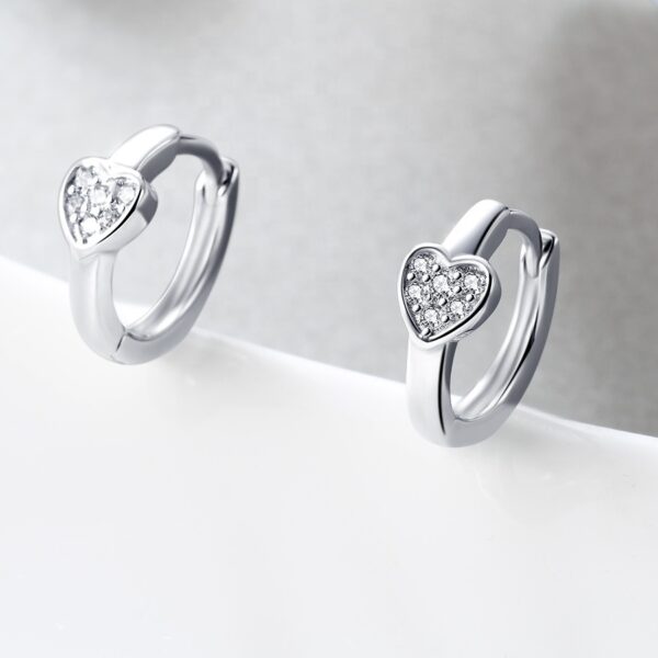 Detail dámských stříbrných náušnic kroužků se srdíčkem a zirkony