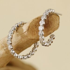 Moderní půlkruhové stříbrné náušnice se zářivými kamínky.