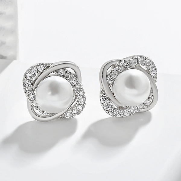 Detailní pohled na dámské stříbrné propletené náušnice s dominantní perlou a zirkony